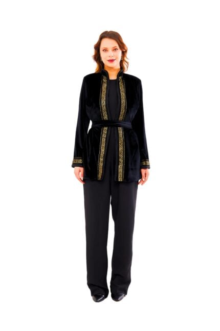 Model wearing the Midnight Velvet Majlis Set: a luxurious black velvet belted jacket featuring intricate gold geometric trim along the stand collar, front opening, and cuffs, styled with matching wide-leg black trousers.