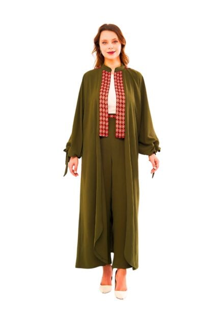 Model wearing the Nomadic Charm Two-Piece Set: an olive-green flowing duster coat with tie-cuff sleeves layered over matching high-waist wide-leg trousers, featuring a contrasting rust geometric embroidered front panel and styled with a white blouse.