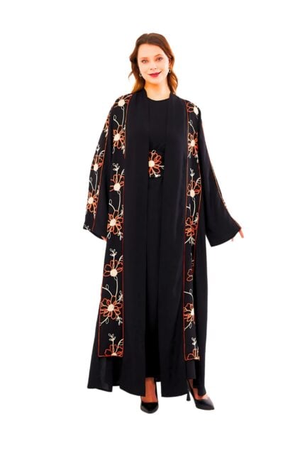 Model wearing the Sunset Bloom Abaya: a flowing black garment adorned with sunset-hued orange and cream floral embroidery along the front panels, cuffs, and matching embroidered waist sash.